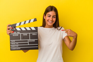 Young caucasian woman holding clapperboard isolated on white background person pointing by hand to...