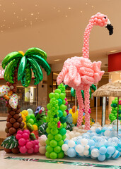 photo zone in Summer Festival style. Balloon decor in pink, green, blue, white and brown. Flamingo figure made of balloons for Childhood