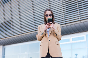 Portrait of young business woman using smartphone. Closeup shot of a businesswoman using a cellphone in the city.