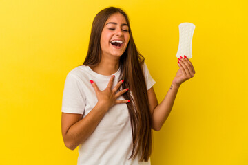Young caucasian woman holding a compress isolated on yellow background laughs out loudly keeping...