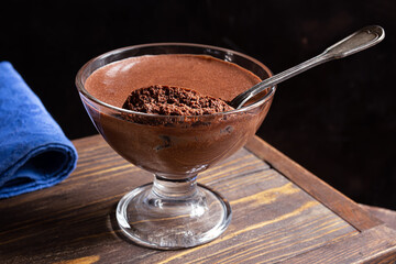 Traditional French chocolate mousse in a transparent bowl on a dark wooden background