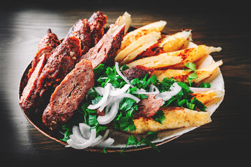 cut Lulia kebab with potato in plate on wooden table background