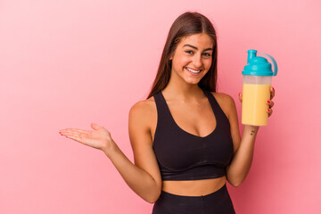 Young caucasian woman holding a protein shake isolated on yellow background showing a copy space on...