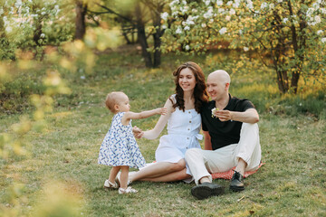 A happy young family with one small child walking having fun laughing spending time together in the park in nature on vacation in the summer outdoors, family day