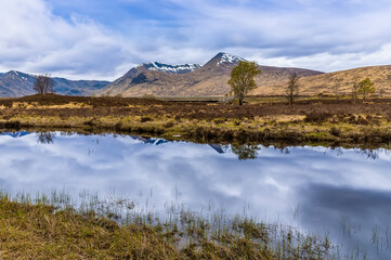 A view across Rannoch Moor and in the shallow waters of Loch Ba near Glencoe, Scotland on a summers day