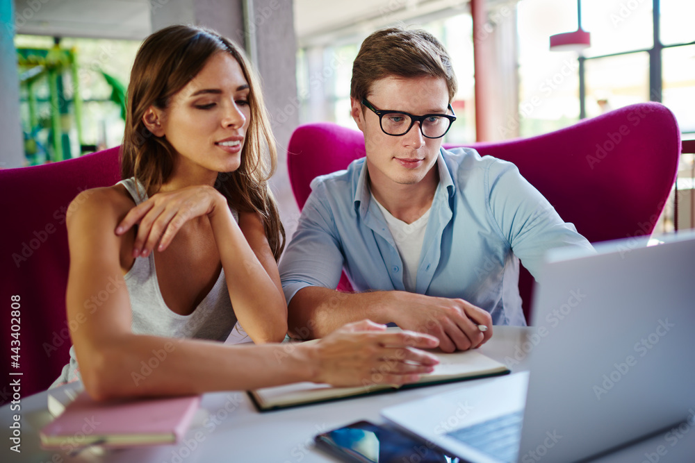 Poster caucasian male and female programmers discussing web projecting using laptop application during free