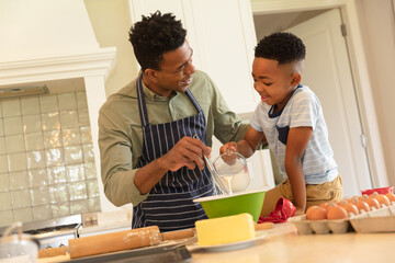 Happy african american father with son baking in kitchen