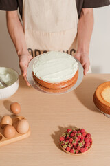 Male pastry chef is holding sponge cake with many various ingredients. Making sponge cake process