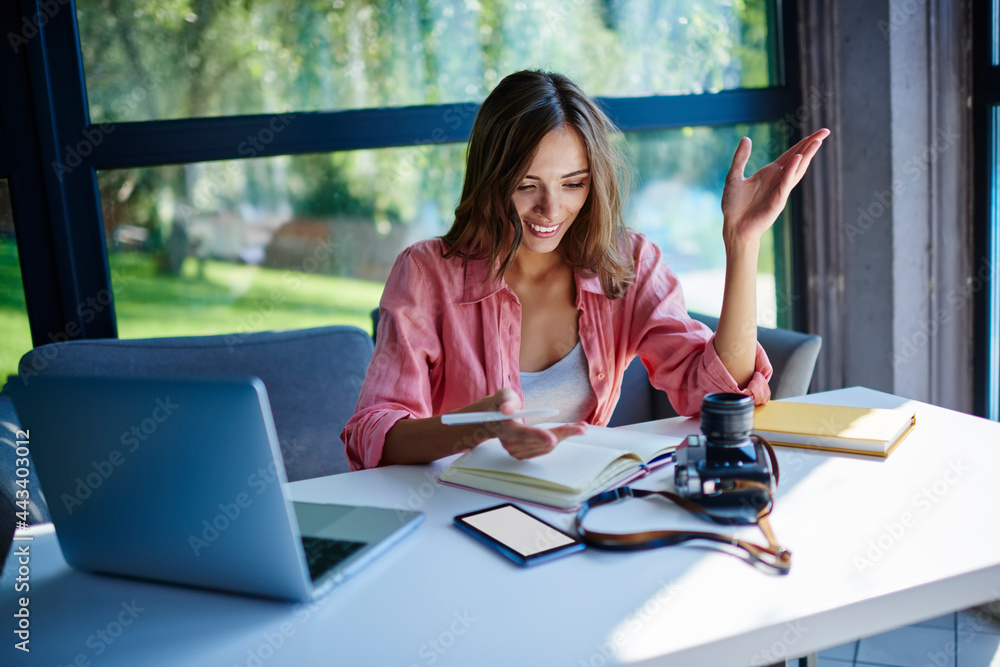 Poster cheerful caucasian woman with textbook sitting at desktop with netbook computer, vintage technology 