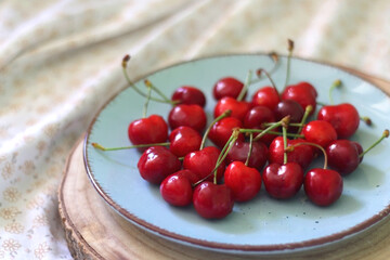 Plate with fresh cherries, served on a bed. Selective focus.
