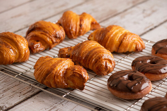 Delicious, fresh croissants and chocolate Donuts on a grid, French breakfast.