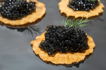 Black caviar in tartlets on a dark background. Healthy food concept.