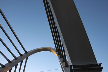 Bottom view of the pylon element and the second pylon with cables of the cable-stayed bridge with red sunset reflections on the metal of the structures 