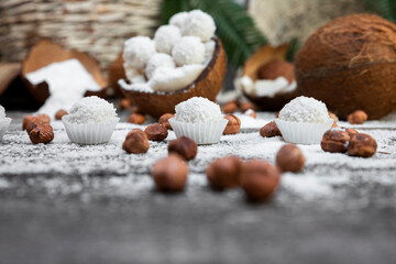Coconut candy, balls, coconuts and hazelnuts on a rustic wooden surface