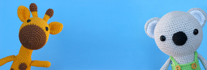 Handmade children's toy - crochet yellow giraffe and koala on a blue background. © iama_sing