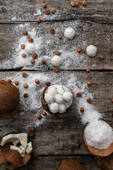 Coconut candy, balls, coconuts and hazelnuts on a rustic wooden surface