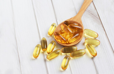 Fish oil capsules on wooden background and texture, Fish oil capsule placed on a wooden spoon, spot...