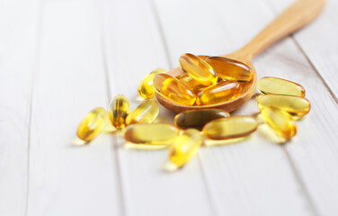 Fish oil capsules on wooden background and texture, Fish oil capsule placed on a wooden spoon, spot focus.