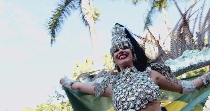 Beautiful Brazilian woman wearing colorful Carnival costume dancing and smiling during Carnaval street parade in city. Cinematic 4K.