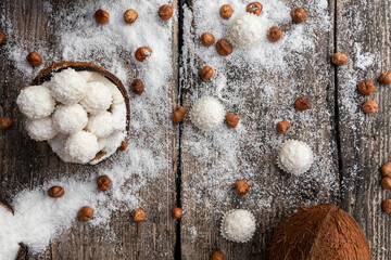 Coconut candy, balls, coconuts and hazelnuts on a rustic wooden surface