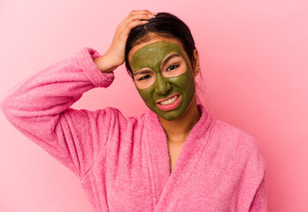 Young Venezuelan woman wearing a bathrobe and facial mask isolated on pink background being shocked, she has remembered important meeting.