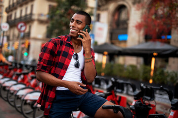 Portrait of handsome african man using electric bike in the city. Happy young man using the phone.