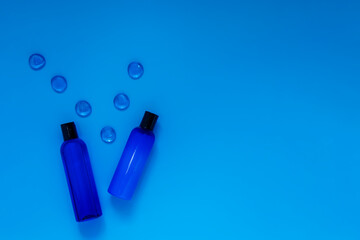 Cosmetic bottles with refreshing shampoo and lotion on a blue background, top view. Packaging for branded products.Blue on blue.