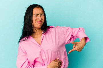 Young Venezuelan woman isolated on blue background having a liver pain, stomach ache.