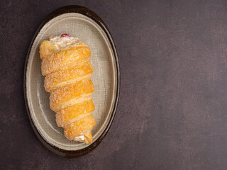 Top view of delicious cream horn filled with vanilla cream on a plate laid on vintage background