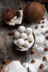 Coconut candy, balls, coconuts and hazelnuts on a rustic wooden surface
