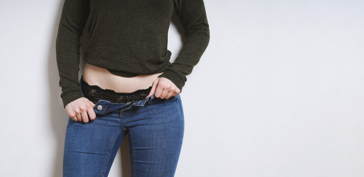 young woman with open jeans showing black lace panties underneath