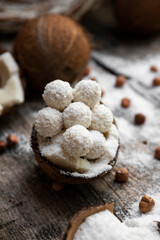 Coconut candy, balls, coconuts and hazelnuts on a rustic wooden surface