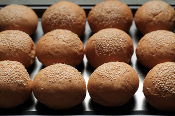 many baked sesame topping burger breads lay on oven tray waiting for cooking, shot with shallow focusing  for using as background wallpaper.
