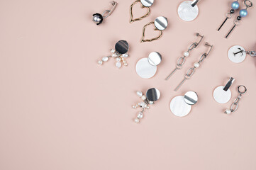 Silver modern stylish earrings on a pink background. Different earrings on a plain pastel...