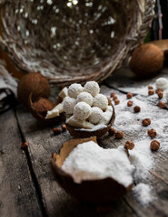 Coconut candy, balls, coconuts and hazelnuts on a rustic wooden surface