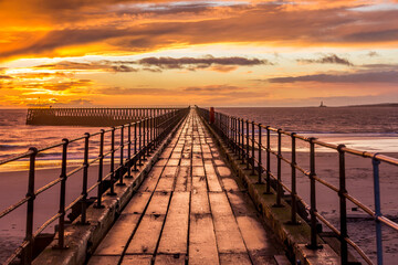 Obraz premium A glorious morning at Blyth beach, with a beautiful sunrise over the old wooden Pier stretching out to the North Sea