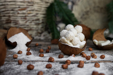 Coconut candy, balls, coconuts and hazelnuts on a rustic wooden surface
