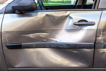 Side view of destroyed car after crash, closeup of dents and scratches on automobile door after...