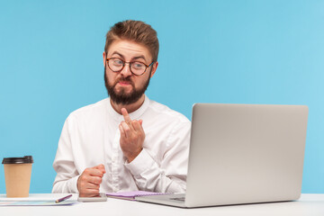 Miserable unkind bearded man office worker showing middle finger on laptop web camera talking video call, denial and disagreement gesture. Indoor studio shot isolated on blue background