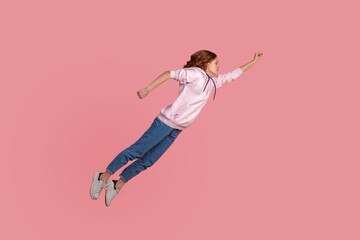 Full length portrait of motivated young female in hoodie and jeans flying in air like hero and...