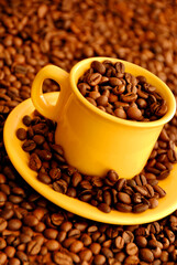 Yellow coffee cup with beans over brown backhround with coffee bean - seeds