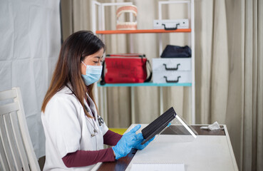 A young asian female doctor working on her tablets sitting in her office. 