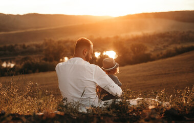Naklejka na ściany i meble Father and kid enjoying sunset in nature