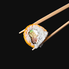 One piece of sushi in chopsticks, isolated on black background. Japanese cuisine concept, copy space banner.