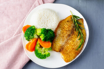 Fish fillet with rice and broccoli. White fish steak baked with vegetables and white rice.