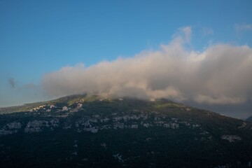 clouds covering the top of a green hill in the rural mountain area of Lebanon
