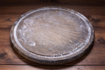 Pizza cutting board and wheat powder flour for homemade bread cooking on table. Wooden tabletop