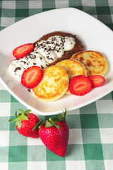 Cottage cheese pancakes, syrniki, ricotta fritters on ceramic plate with fresh strawberry.