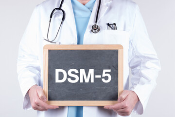 Doctor holding a blackboard with DSM-5 written on it