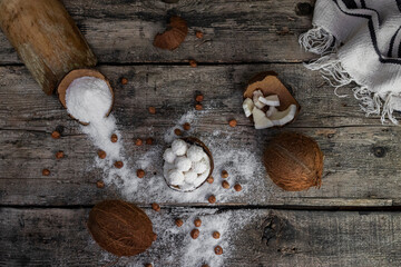 Coconut candy, balls, coconuts and hazelnuts on a rustic wooden surface